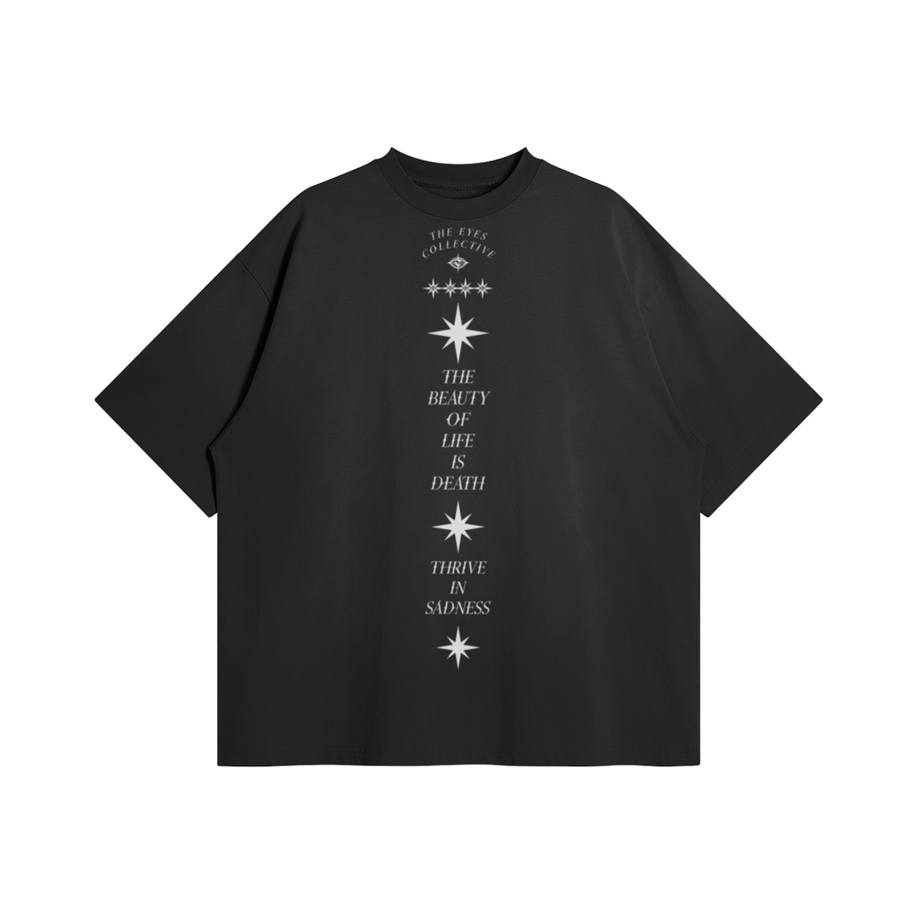 Sad Times Tee by THE EYES in washed black, front view with a vertical star graphic and The Beauty of Life Is Death and Thrive in Sadness lettering.